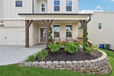 Entrance to property with brick siding, board and batten siding, concrete driveway, and an attached garage
