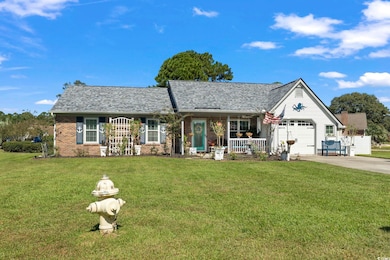 View of front of house featuring covered porch, a front lawn, concrete driveway, brick siding, and a garage