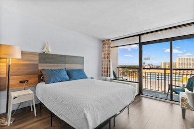 Bedroom featuring expansive windows, wood finished floors, access to exterior, and a city view