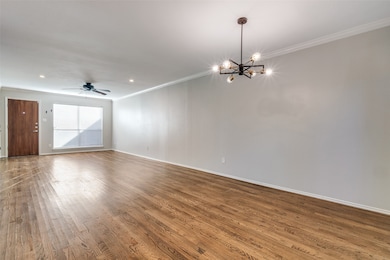Spare room with hardwood / wood-style floors, crown molding, and ceiling fan with notable chandelier