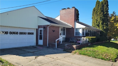 View of front of property with a front lawn, driveway, brick siding, and an attached garage