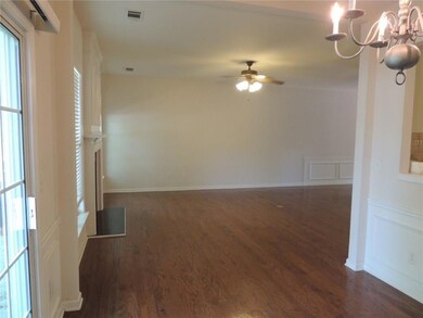 Empty room with a chandelier, dark wood-style floors, ceiling fan, and a decorative wall