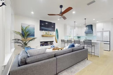 Living room with ceiling fan, a glass covered fireplace, recessed lighting, and light wood finished floors