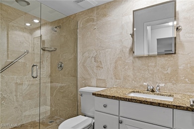 Bathroom with vanity, a shower with door, toilet,