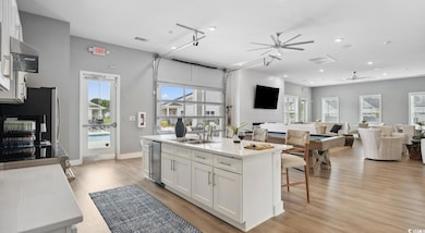 Kitchen featuring ceiling fan, white cabinetry, a kitchen island with sink, open floor plan, and light wood-type flooring