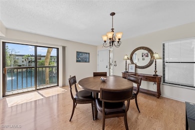 Dining room with a chandelier, light wood-style floors, a textured ceiling, and baseboards