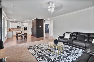 Living room with crown molding, ceiling fan, recessed lighting, and wood finished floors