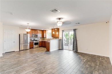 Kitchen with brown cabinets, pendant lighting, stainless steel appliances, light countertops, and​​‌​​​​‌​​‌‌​​​‌​‌​​​‌‌​​​‌‌​​​​​​‌‌​‌‌‌ backsplash