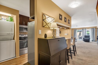 Kitchen featuring estacked washer and dryer, appliances with stainless steel finishes, dark brown cabinets, a kitchen breakfast bar, and open floor plan