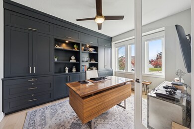 Office area with a ceiling fan and light wood-style floors