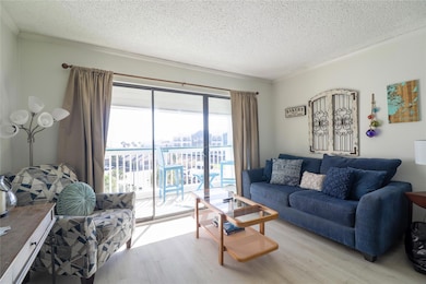 Living room with a textured ceiling, wood finished floors, and ornamental molding