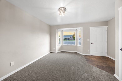 Empty room featuring dark colored carpet and baseboards