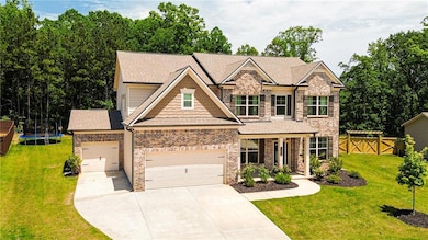 View of front of home featuring brick siding, concrete driveway, roof with shingles, and a trampoline
