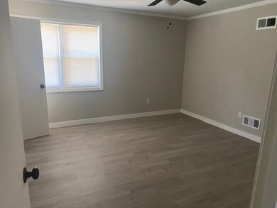 Spare room with a ceiling fan, ornamental molding, wood finished floors, and baseboards