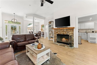 Living area with ornamental molding, ceiling fan, a fireplace, light wood-style flooring, and a chandelier