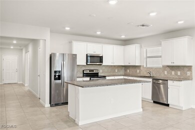 Kitchen featuring appliances with stainless steel finishes, tasteful backsplash, a center island, white cabinetry, and recessed lighting