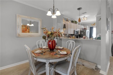 Dining room with crown molding, visible vents, lig