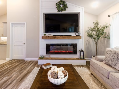 Living room with lofted ceiling, light wood-style flooring, and a large fireplace