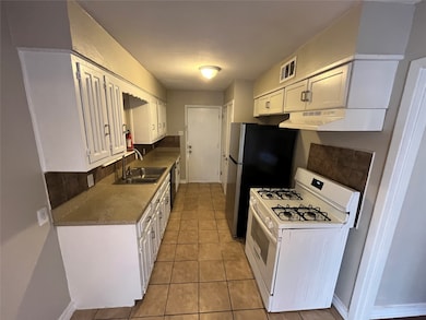 Kitchen with white cabinets, gas range gas stove, light tile patterned floors, and tasteful backsplash