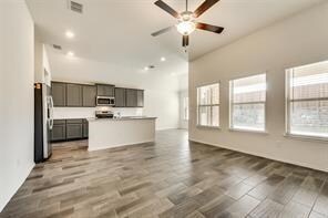 Kitchen featuring refrigerator, ceiling fan, hardwood / wood-style floors, and an island with sink