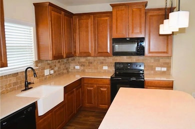 Kitchen with black appliances, a sink, light coun