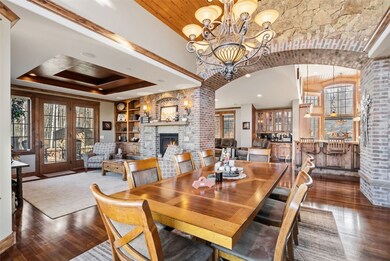 Dining room featuring healthy amount of natural light, a fireplace, dark wood-style flooring, and a chandelier