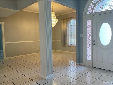 Foyer with ornamental molding, healthy amount of natural light, decorative columns, and light tile patterned floors
