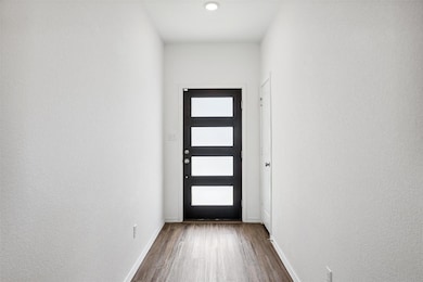 Doorway with dark wood-style floors and baseboards