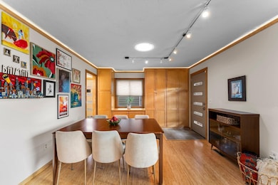 Adjacent to the kitchen, the dining room is located at the front of the home and provides direct access to the front entry. It includes abundant built-in cabinetry for storage, hardwood floors, and modern track lighting.