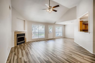 Unfurnished living room with a fireplace, high vaulted ceiling, wood finished floors, and a ceiling fan