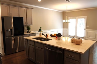 Kitchen featuring stainless steel appliances, gray cabinetry, a kitchen island with sink, decorative light fixtures, and a chandelier