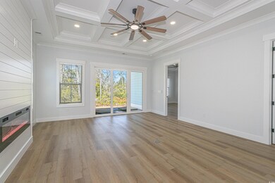 Unfurnished living room with light wood-style floors, ceiling fan, coffered ceiling, and beamed ceiling