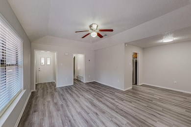 Unfurnished living room with light wood-style floors, a textured ceiling, ceiling fan, and vaulted ceiling