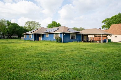 Rear view of property with solar panels and a lawn