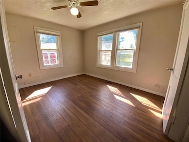 Unfurnished room with dark wood-type flooring, a textured ceiling, and ceiling fan