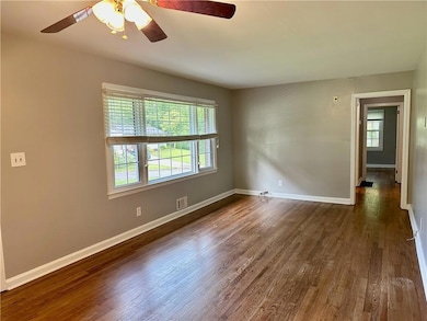 Spare room featuring dark wood-type flooring, baseboards, and ceiling fan