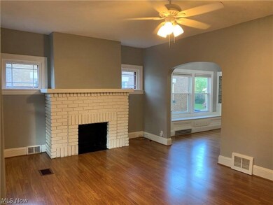 Unfurnished living room featuring ceiling fan, a brick fireplace, and dark wood-type flooring