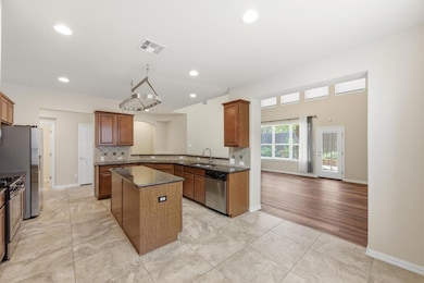 Kitchen featuring tasteful backsplash, brown cabinetry, a center island, dark stone counters, and light tile patterned flooring