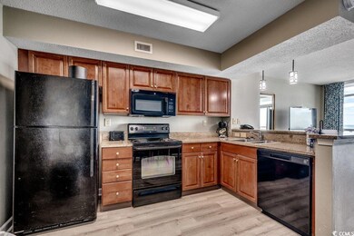 Kitchen featuring black appliances, brown cabinets, a peninsula, and light wood-style floors