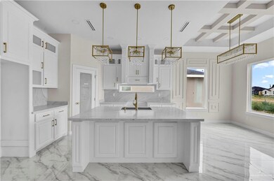 Kitchen featuring a chandelier, light marble finish floors, white cabinets, glass insert cabinets, and coffered ceiling