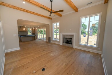 Unfurnished living room with a fireplace, beamed ceiling, a ceiling fan, light wood-style floors, and crown molding