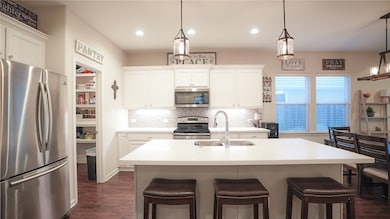 Kitchen featuring stainless steel appliances, dark wood-style floors, backsplash, white cabinetry, and recessed lighting