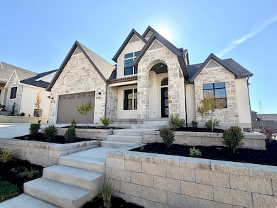 French country home featuring stone siding, concrete driveway, a garage, and a shingled roof