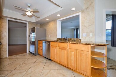 Kitchen featuring stainless steel appliances, ornamental molding, ceiling fan, a sink, and dark stone counters