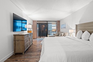 Bedroom with a textured ceiling, access to outside, dark wood-type flooring, and baseboards