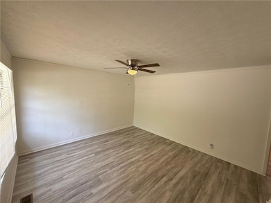 Unfurnished room with a textured ceiling, wood finished floors, and a ceiling fan