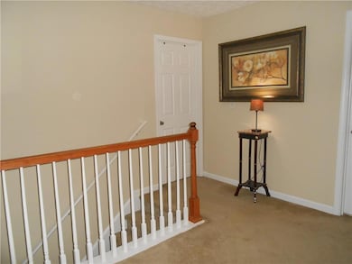 Hall with an upstairs landing, carpet, and baseboa
