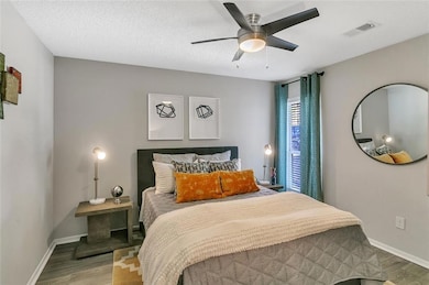 Bedroom with ceiling fan, a textured ceiling, and hardwood / wood-style flooring