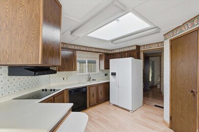 Kitchen with black appliances, light countertops, light wood-style flooring, backsplash, and wallpapered walls