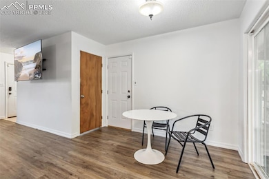 Living area featuring wood finished floors, a textured ceiling, and baseboards